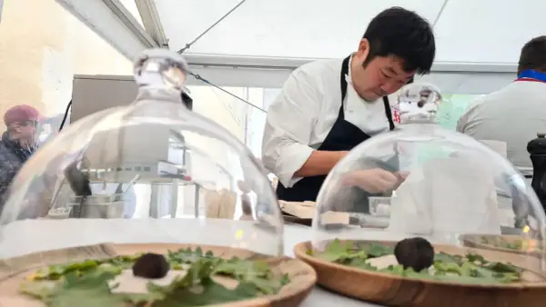 Chef prépare des mets délicats sous cloche, peut-être inspirés par le vignoble de Meursault.