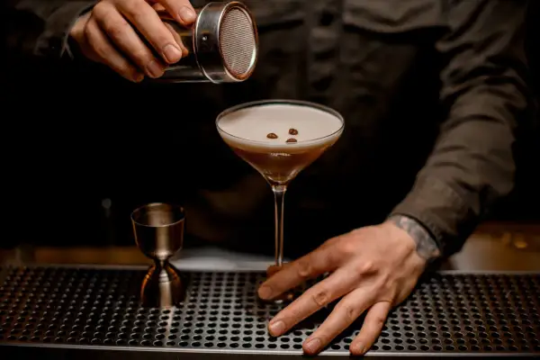 Un barman termine la préparation du cocktail du moment, saupoudrant des grains de café sur la mousse onctueuse d'un verre à martini.