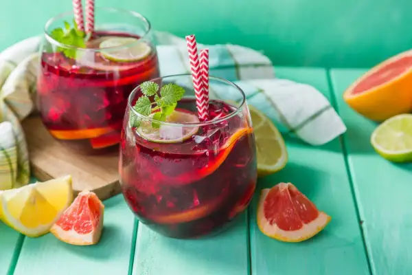 Deux verres de sangria rouge vif, garnis de fruits et de menthe, prêts à être dégustés. Le vin pour sangria est parfait pour les journées chaudes.