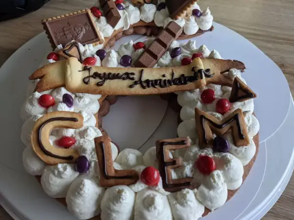 Gâteau décoré de crème fouettée, biscuits en forme de lettres formant "CLEM", chocolats et bonbons. Quelle crème pour recouvrir un gâteau, celle-ci est parfaite !