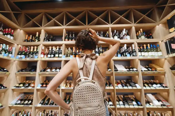Une femme choisit une bouteille dans une cave à vin, un paradis pour tout négociant en vin.