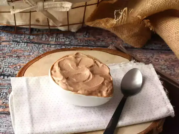 Une cuillère attend patiemment à côté d'un bol rempli d'une onctueuse ganache Nutella, prête à être dégustée.