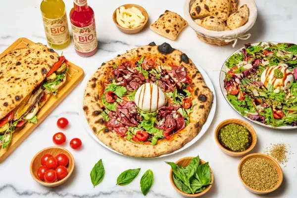 Une pizza savoureuse, un sandwich garni, une salade fraîche et des boissons. Quel vin avec pizza ? Un repas italien parfait pour partager.