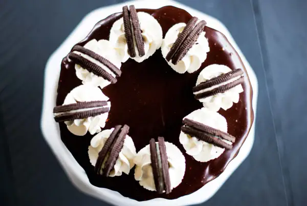 Gâteau au chocolat glacé, décoré de crème fouettée et de biscuits Oreo. Un délice pour les amateurs de layer cake Oreo.