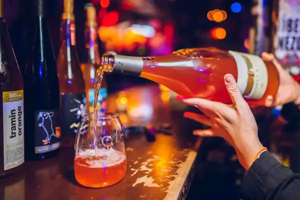 Un verre se remplit d'un vin orange pétillant, promesse d'un moment convivial. Le meilleur vin orange pour une soirée réussie.