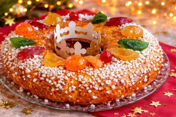 Gâteau des Rois orné de fruits confits et d'une couronne en papier, prêt à être dégusté. Une belle idée pour une recette de gâteau des rois festive.