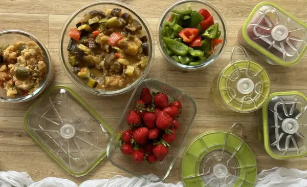 Préparation pour le batch cooking du goûter : ratatouille, poivrons coupés, fraises et autres ingrédients dans des boîtes hermétiques.