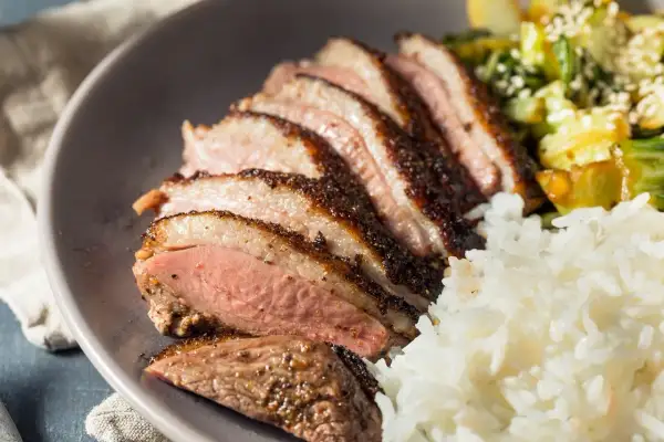 Tranches de magret de canard, riz blanc et légumes. Un plat savoureux qui invite à se demander : que boire avec du magret de canard ?