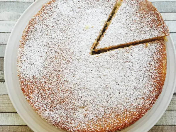 Un délicieux victoria sponge cake, saupoudré de sucre glace, avec une part déjà coupée. Parfait pour le thé !